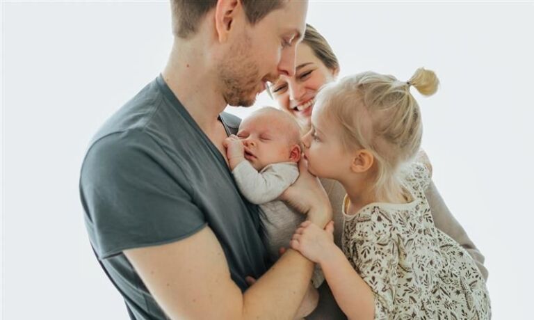 Eine Familie mit Neugeborenem umarmt sich.