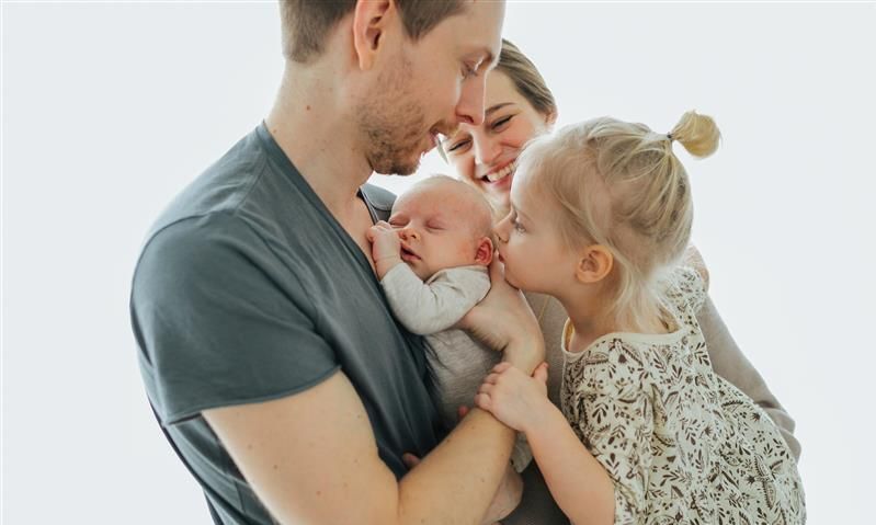 Eine Familie mit Neugeborenem umarmt sich.