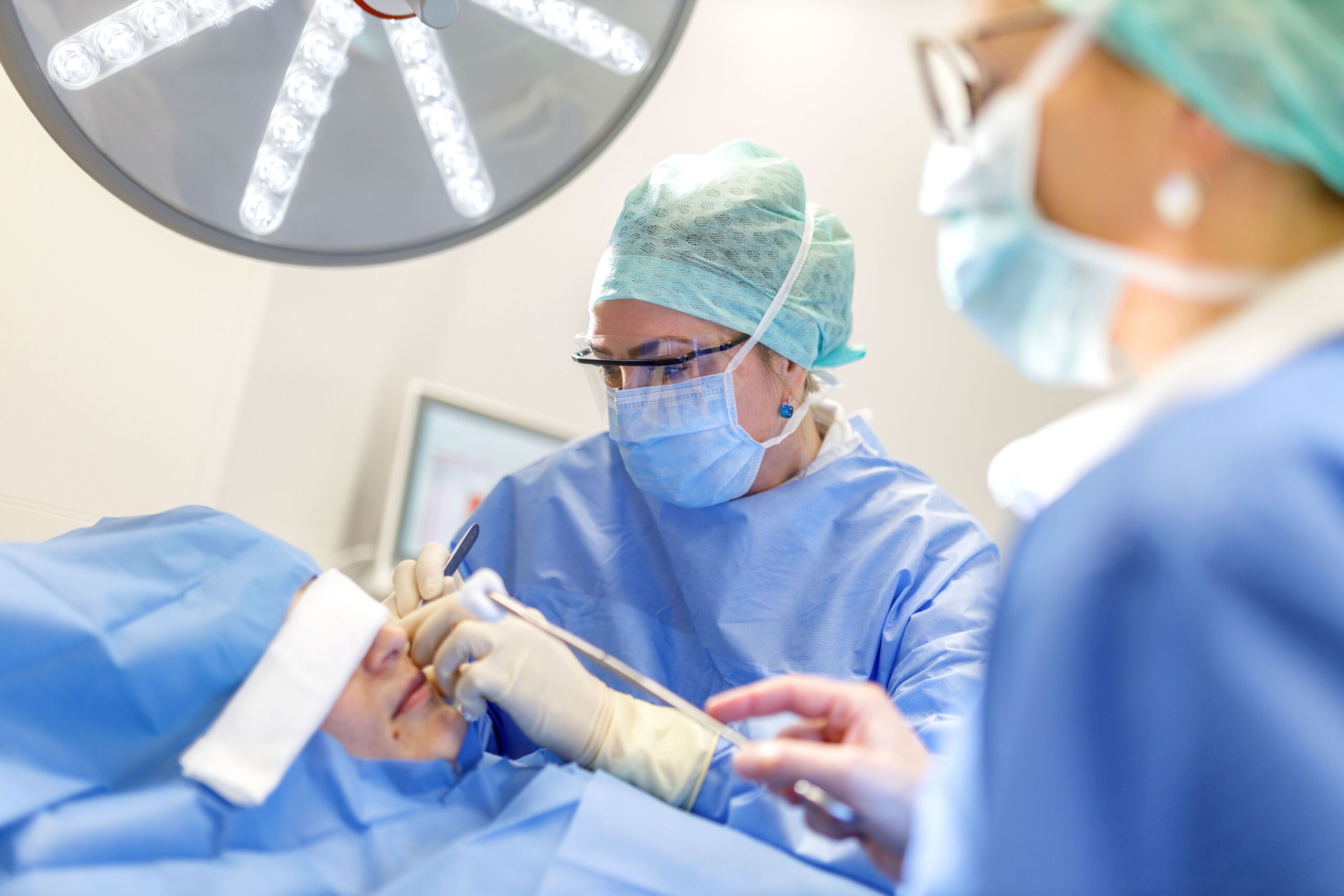Zwei Chirurgen führen eine Nasenoperation an einem Patienten durch
