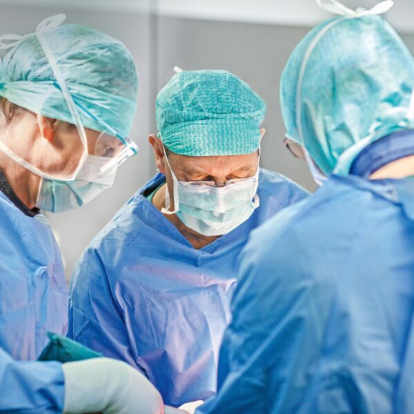 Drei Chirurgen operieren an einem Patienten