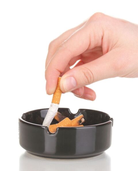 Hand stubbing out the cigarette in ashtray.