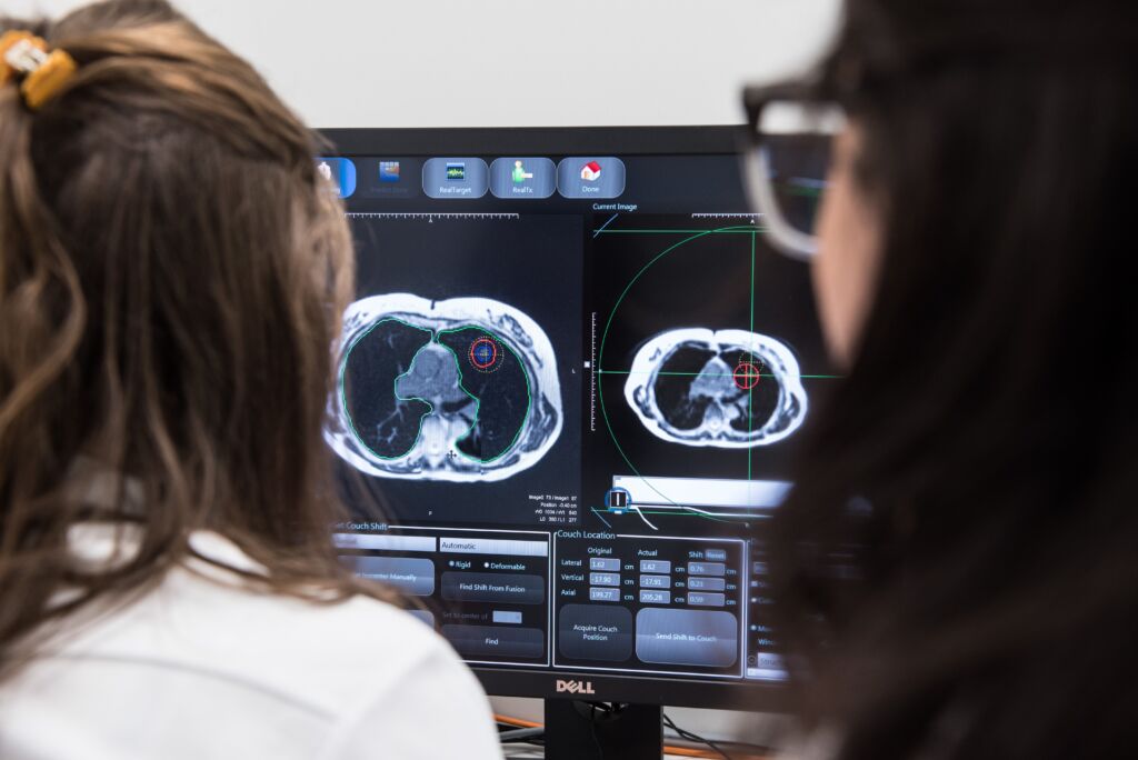Zwei Frauen schauen sich die MRI Bilder auf einem Bildschirm an