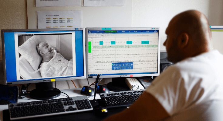 Ein Pfleger überwacht an einem Bildschirm einen Patienten
