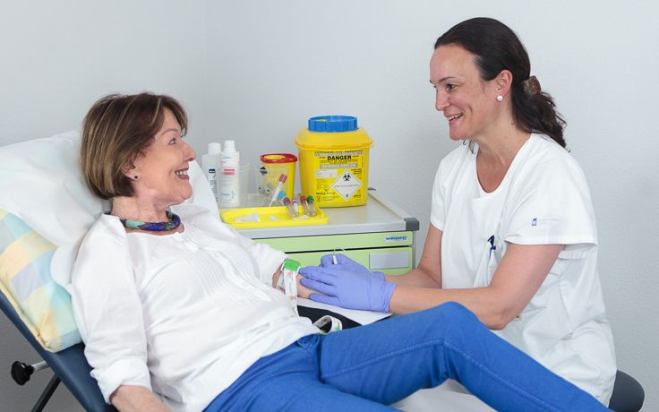 Eine Pflegerin führt eine Blutentnahme bei einer Patientin druch