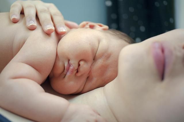 Schlafendes Baby bei einer Frau liegend