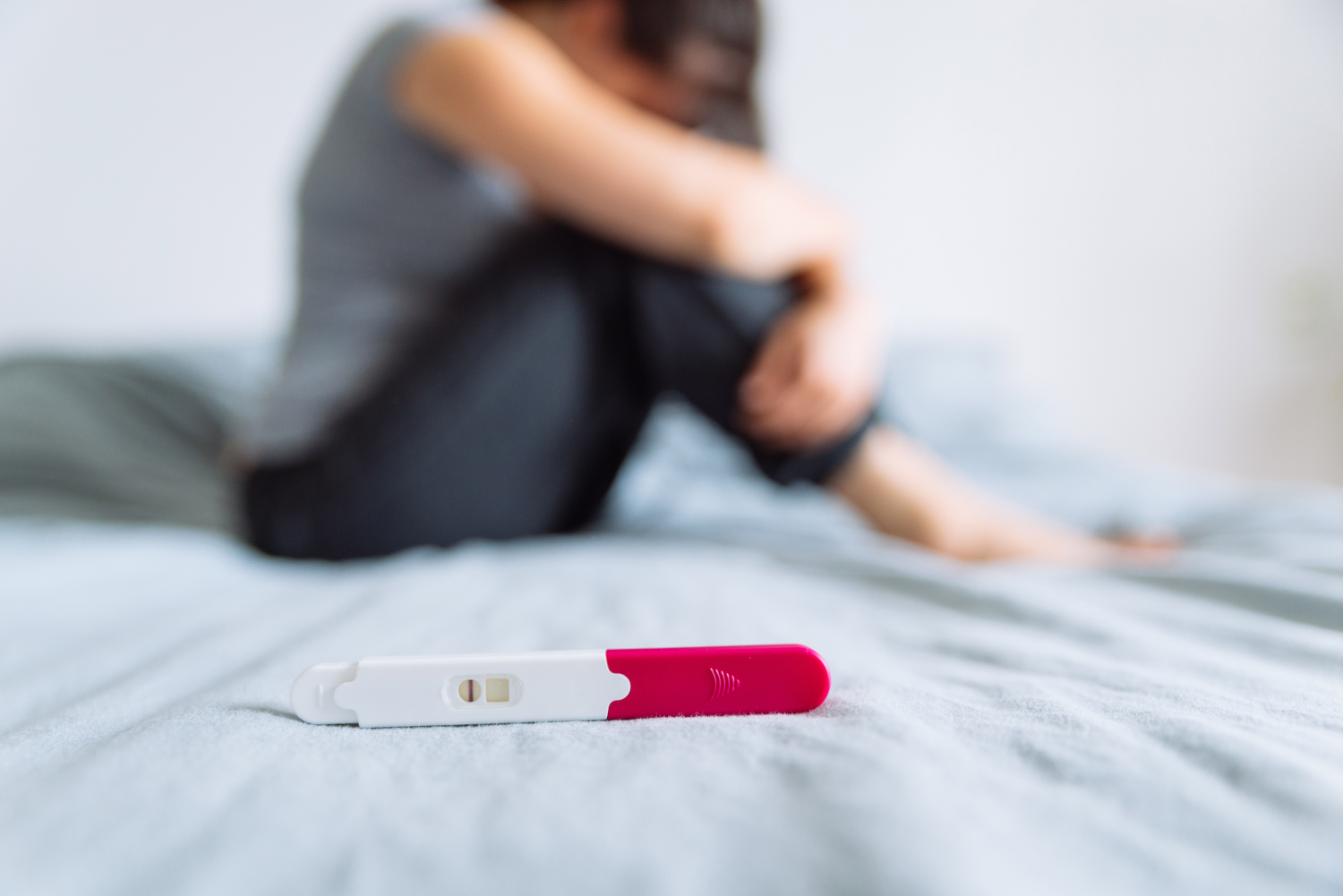 Schwangerschaftstest negativ mit Frau im Hintergrund