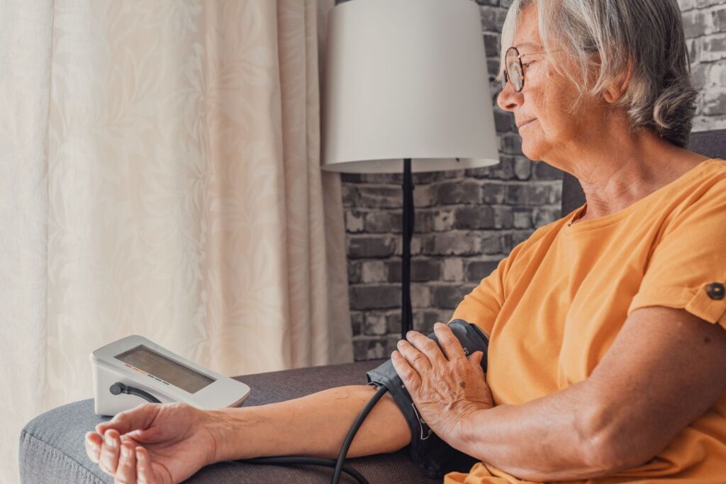 Elderly lady measures her blood pressure with a measuring device while seated