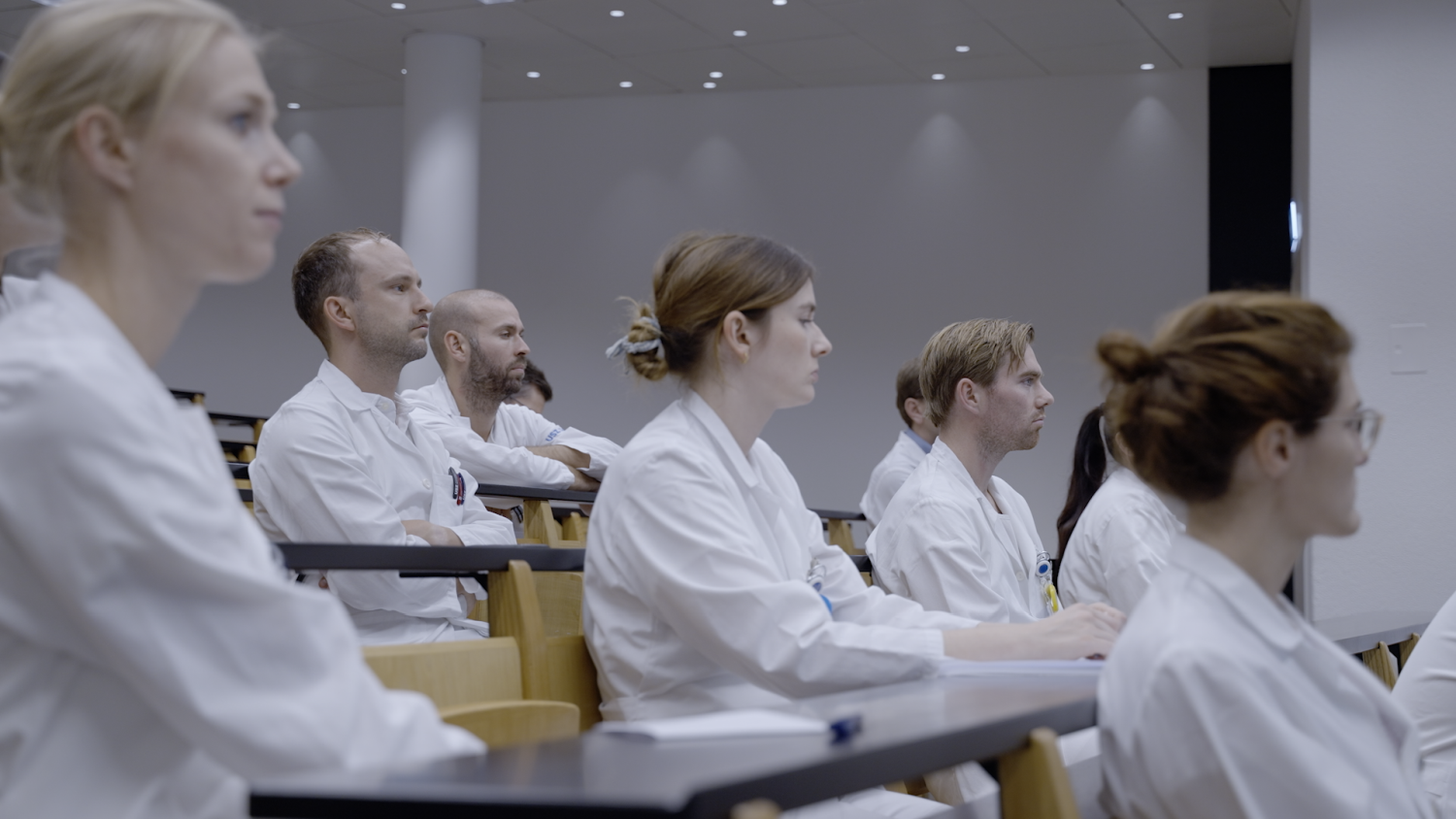 Ärzte sitzen in einer Reihe und schauen alle nach vorne