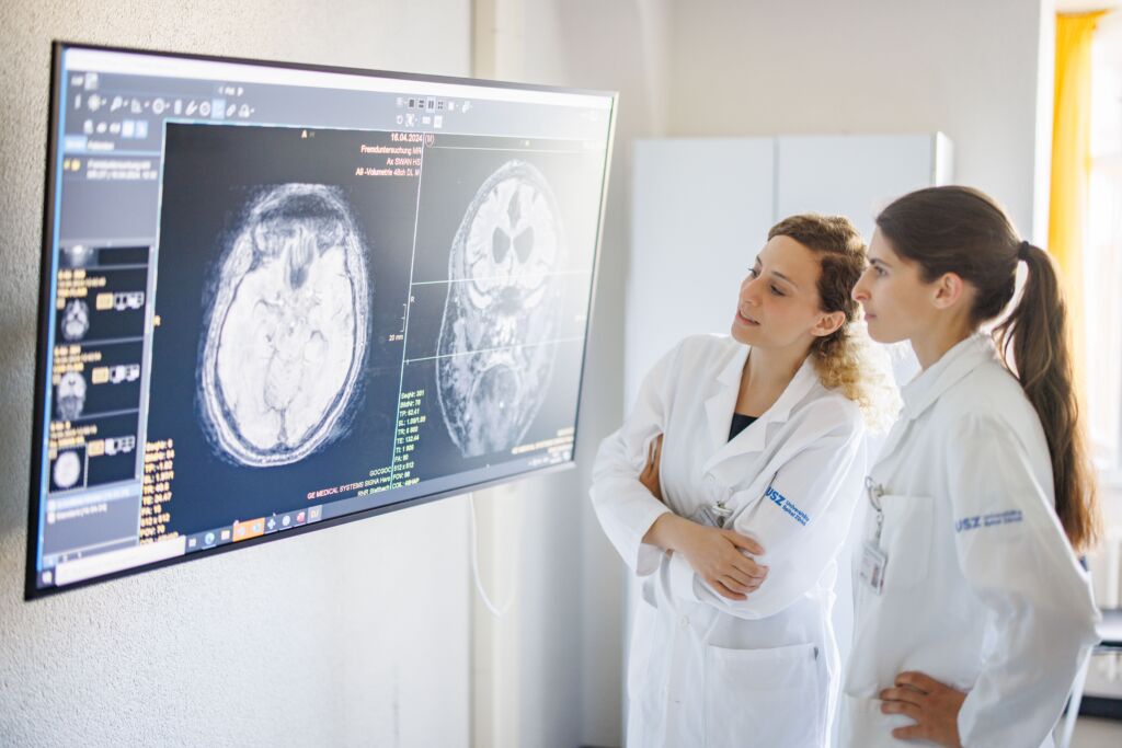 Zwei Ärztinnen schauen auf ein MRI-Bild eines Hirnes