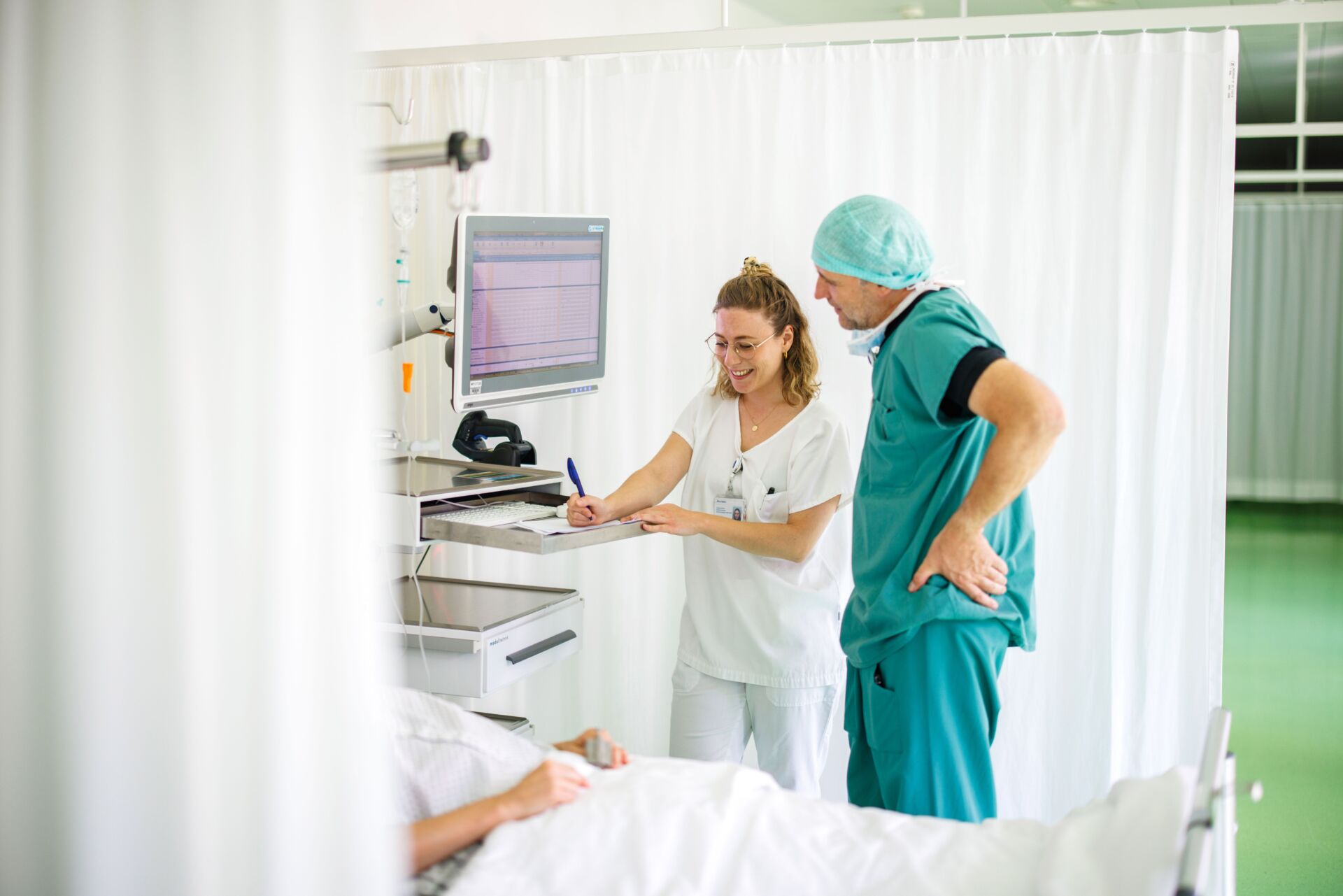 Eine Pflegerin und ein Arzt besprechen am Patientenbett.