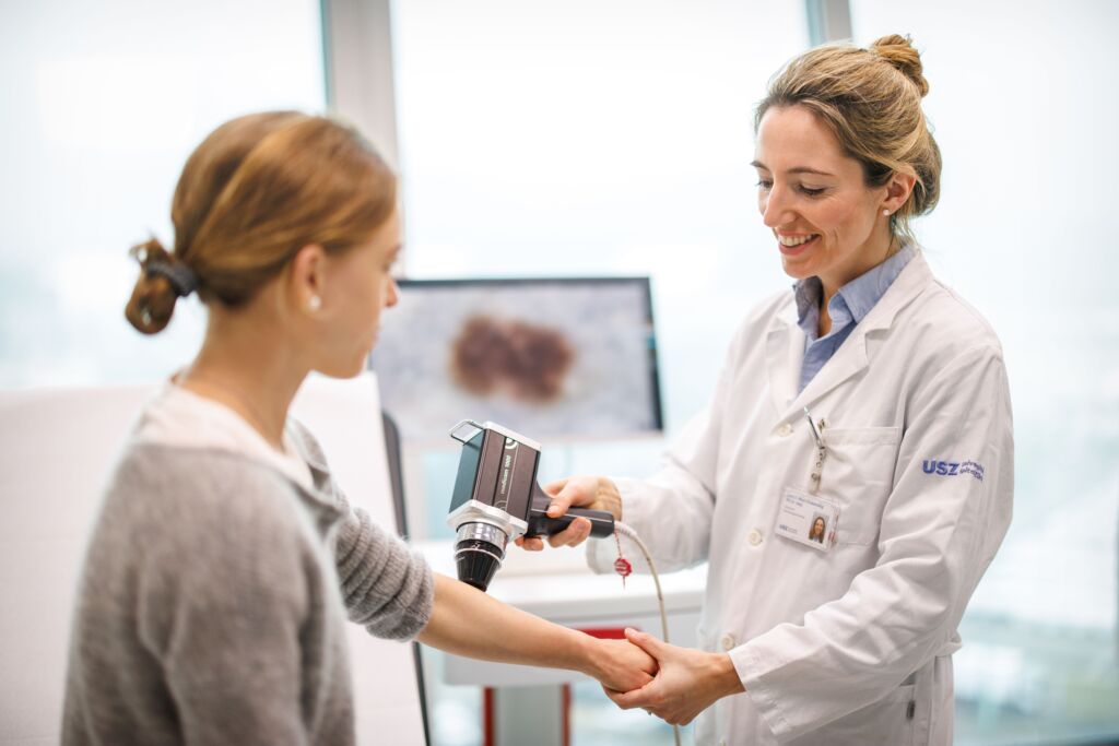 Dermatologin untersucht Arm der Patientin mit Foto Finder