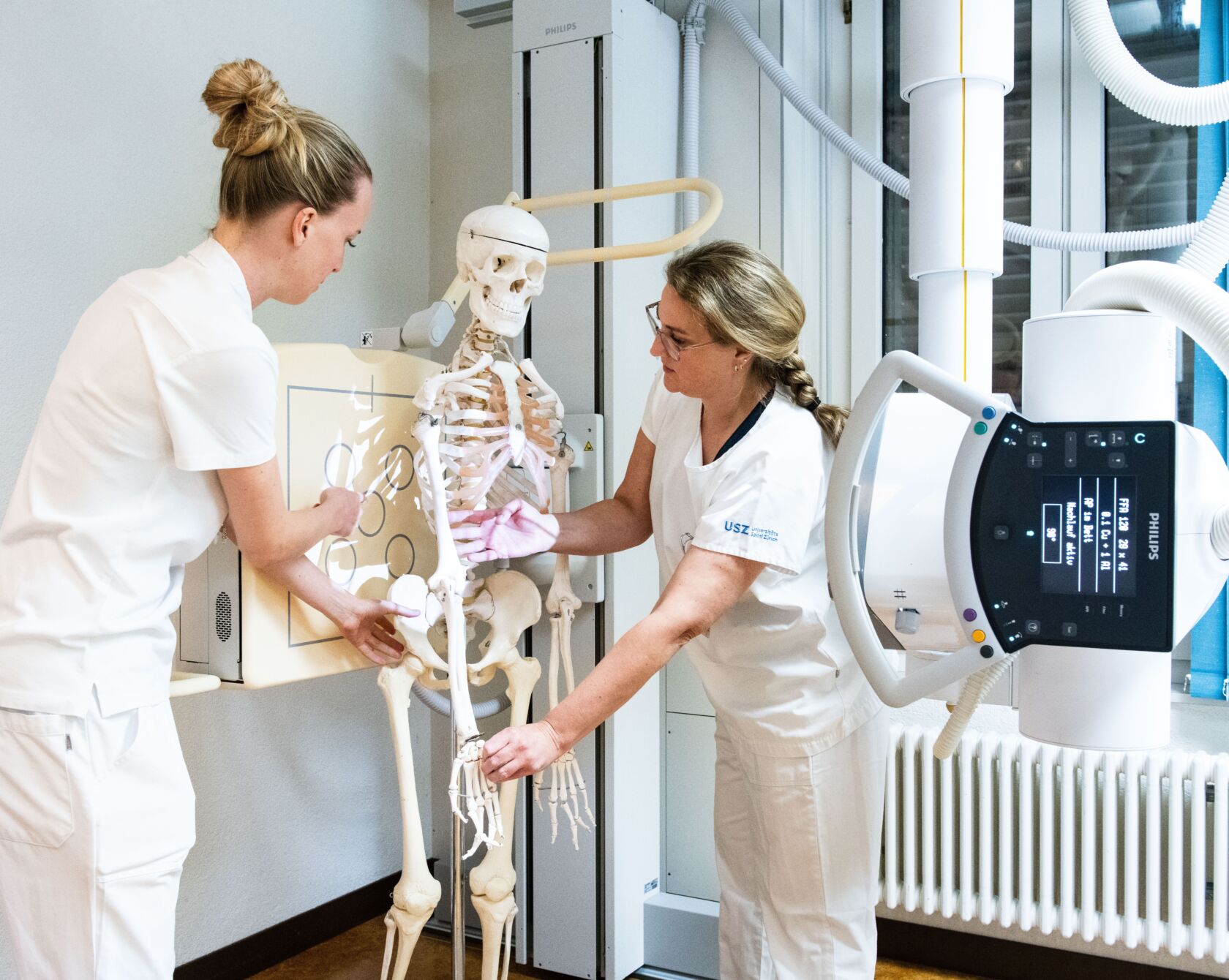 Radiologiefachfrauen arbeiten an einer Skelett-Puppe.
