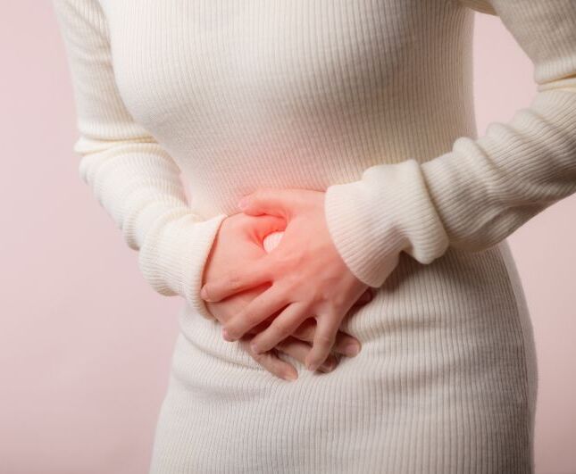 Frau hält sich schmerzhaft den Bauch.