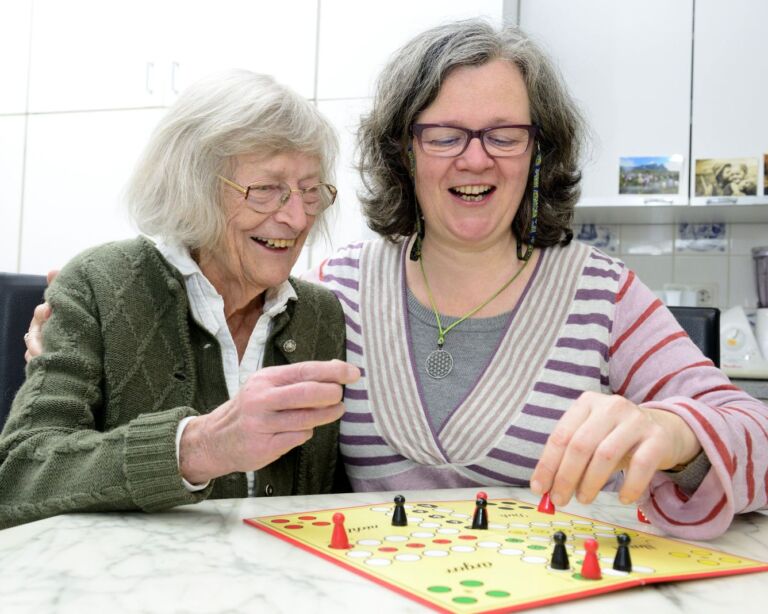 Ältere Person und Betreuungsperson mit Brettspiel