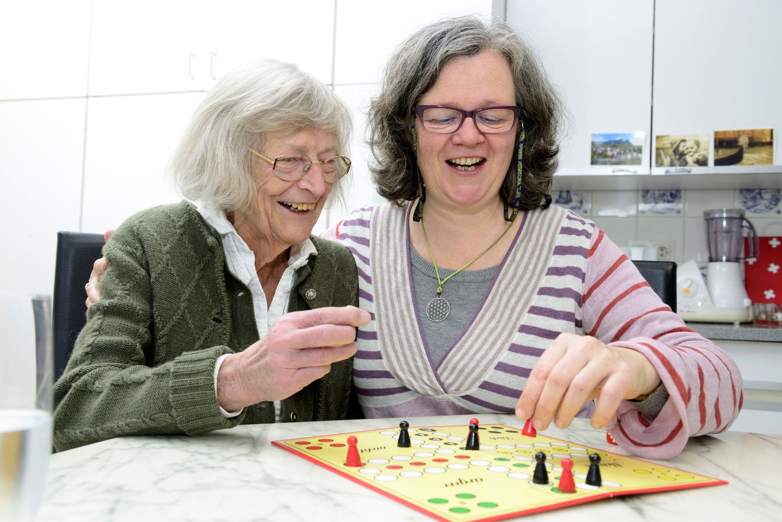 Ältere Person und Betreuungsperson mit Brettspiel