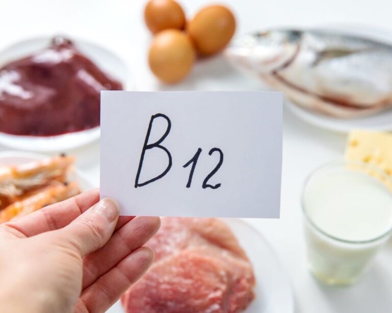 Hand mit Zettel B12, im Hintergrund Lebensmittel