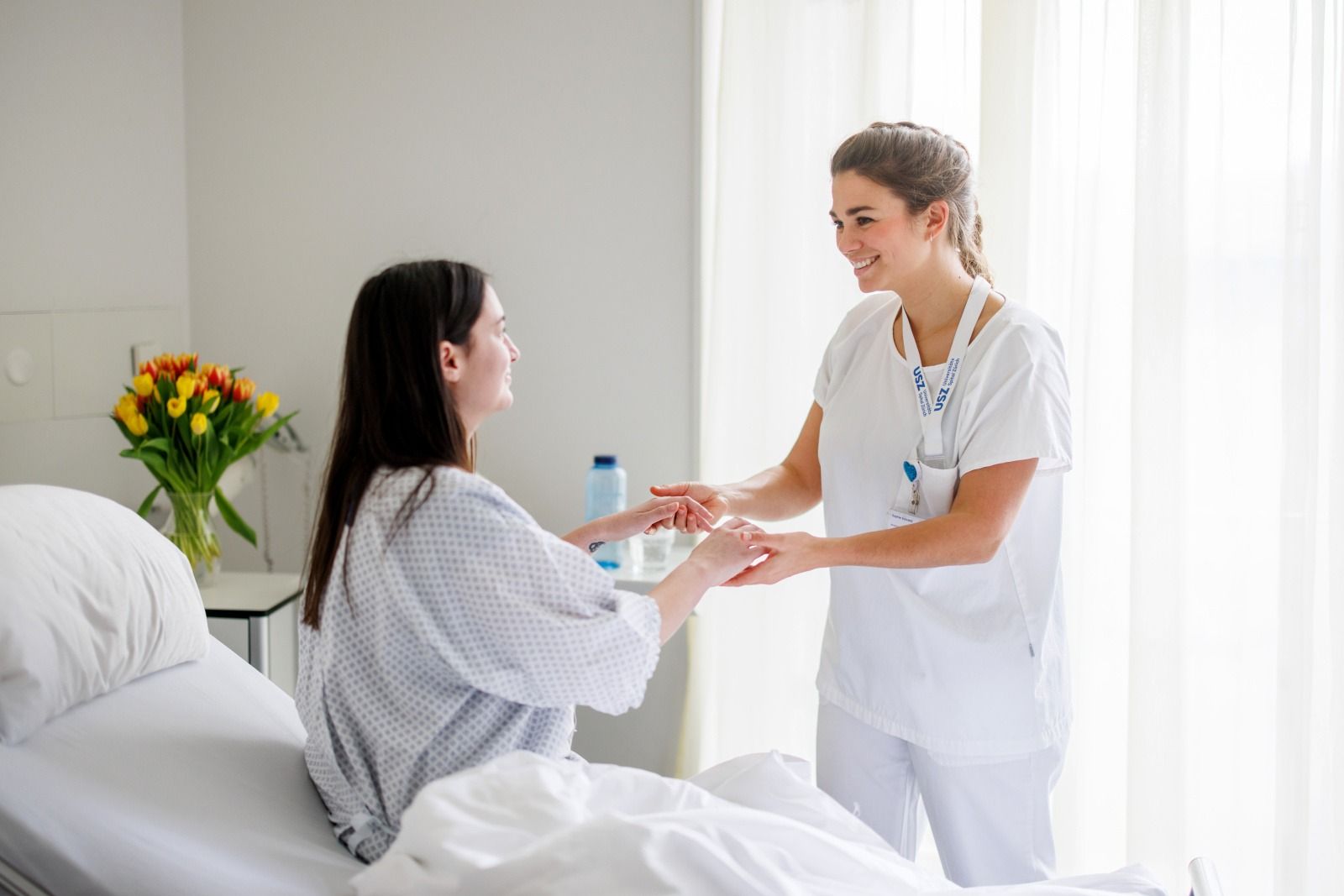 Pflegefachperson hilft Patientin beim Aufstehen