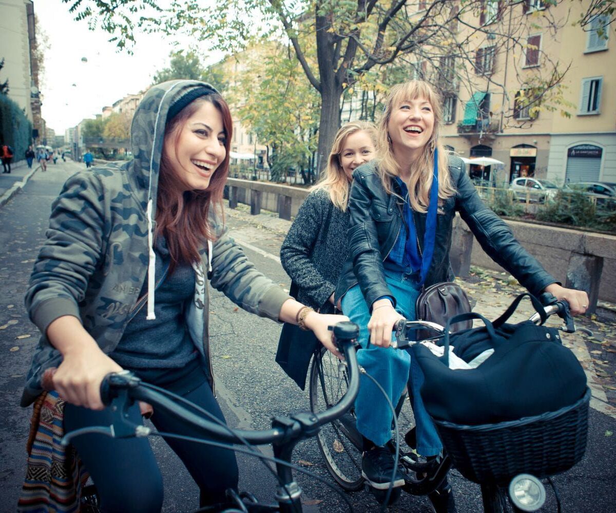 Drei junge Frauen mit Fahrrad unterwegs
