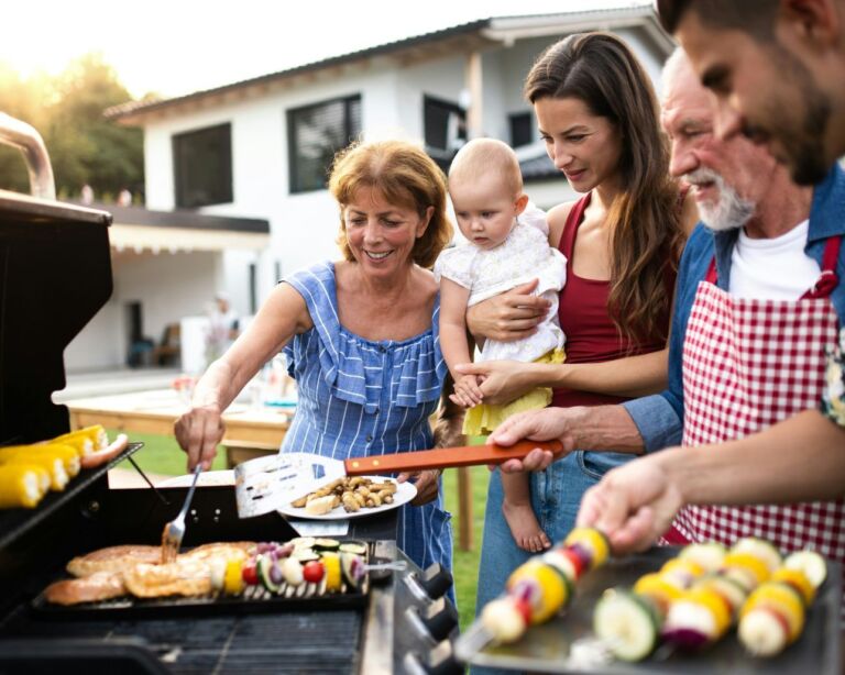 Familie steht um Grill
