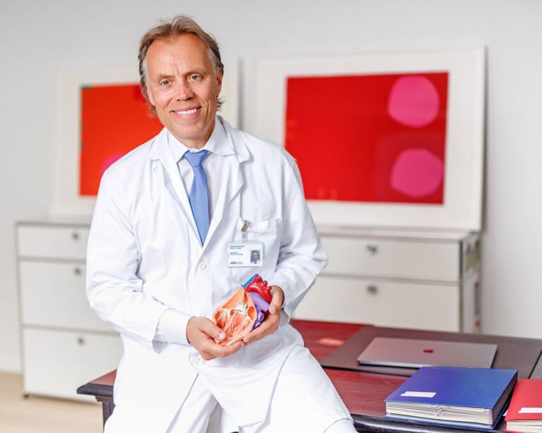 Frank Ruschitzka sitzt im Büro und hält Herz-Model in der Hand