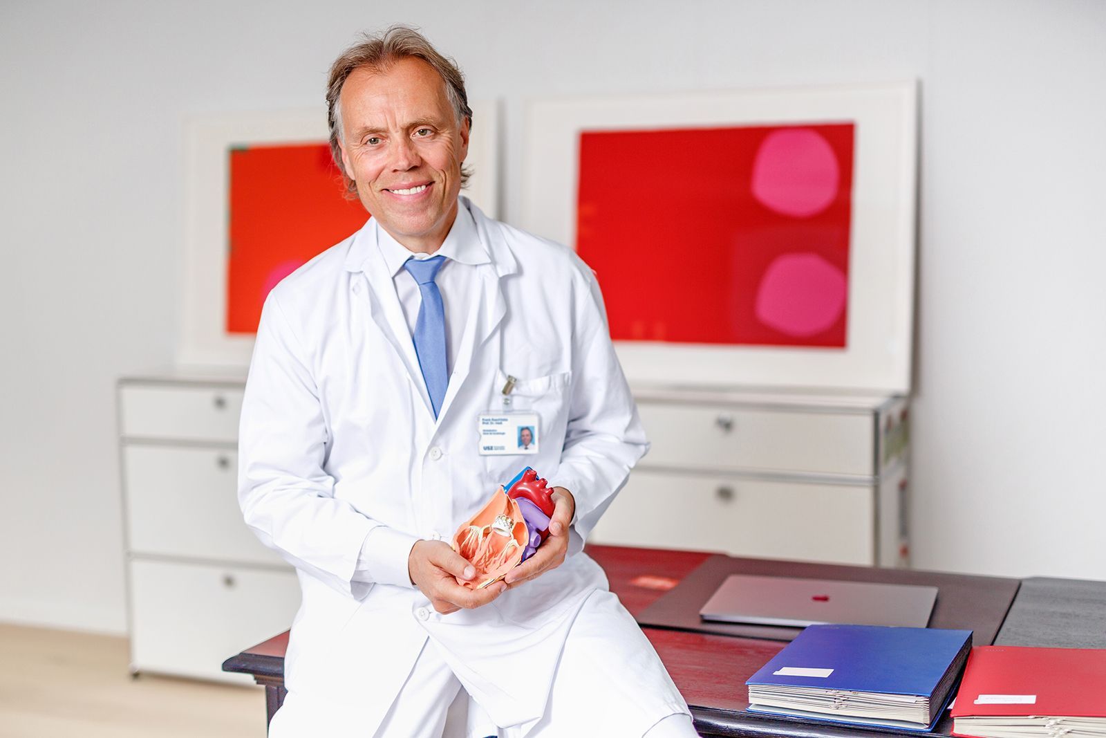 Frank Ruschitzka sitzt im Büro und hält Herz-Model in der Hand