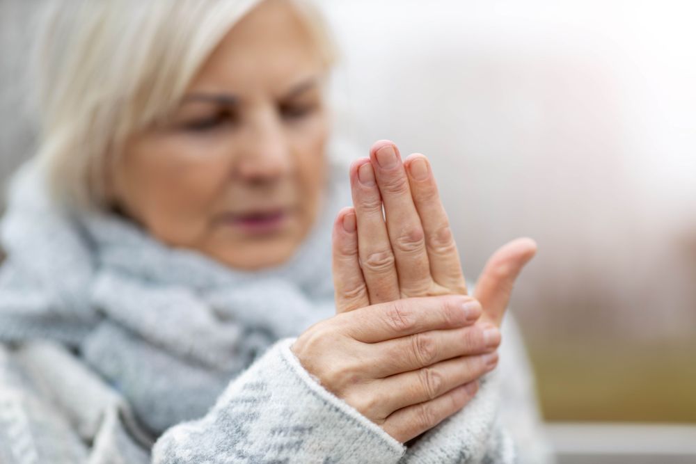 Frau hält sich mit einer Hand die andere schmerzhaft