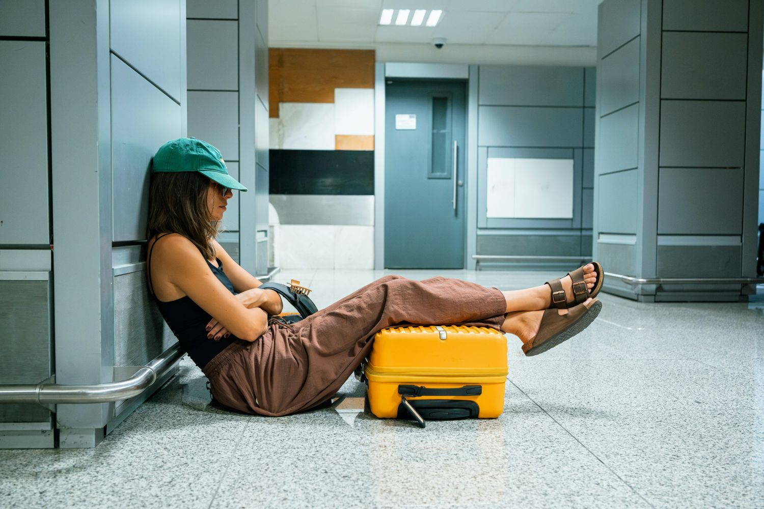 Frau sitzt am Flughafen mit Koffer unter den Beinen und döst