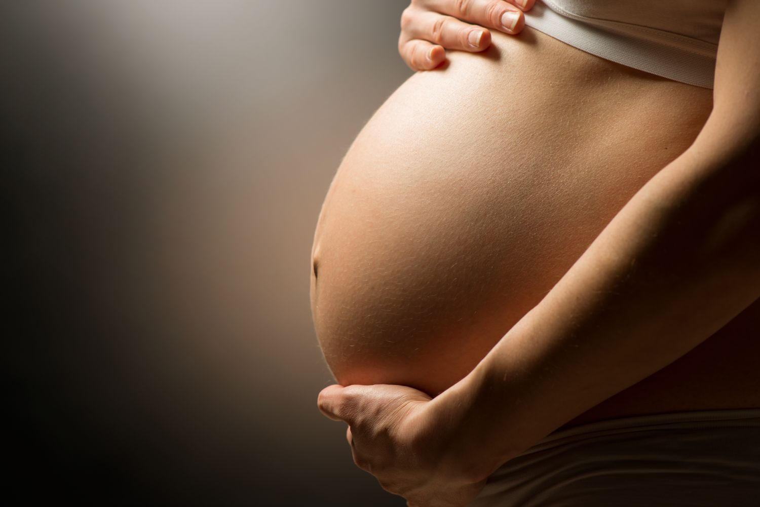 Frau hält sich Bauch in der Schwangerschaft