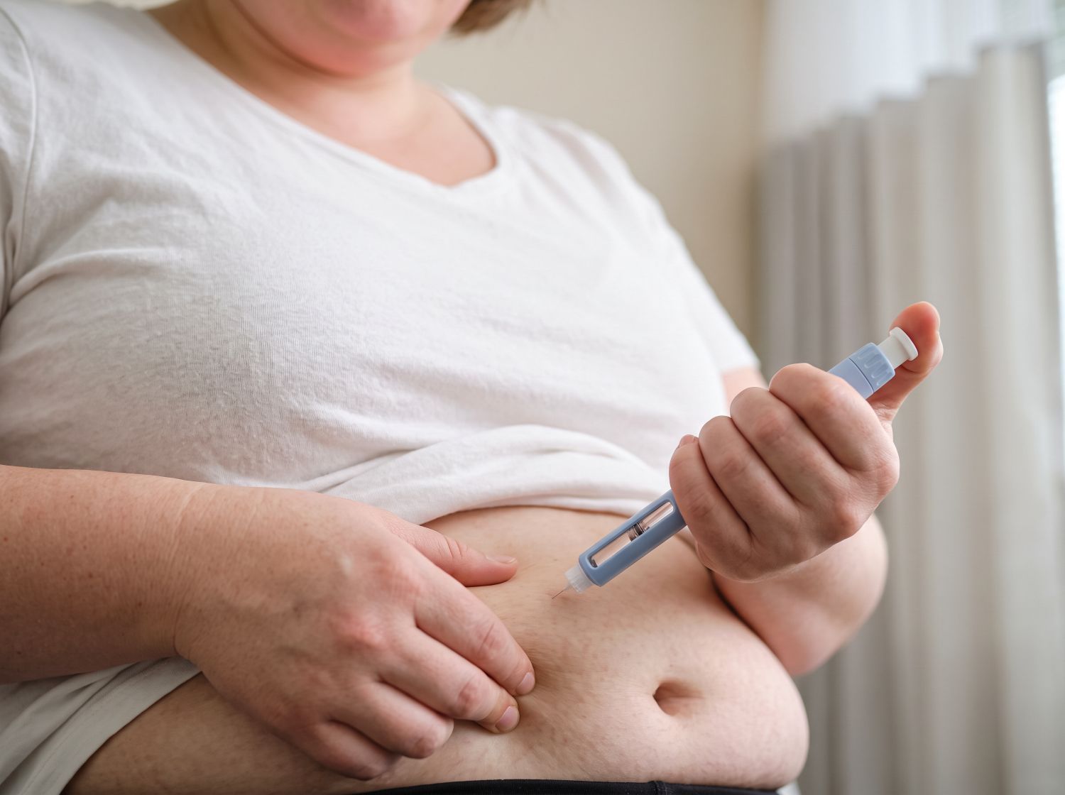 Frau spritzt sich Medikament in Bauch