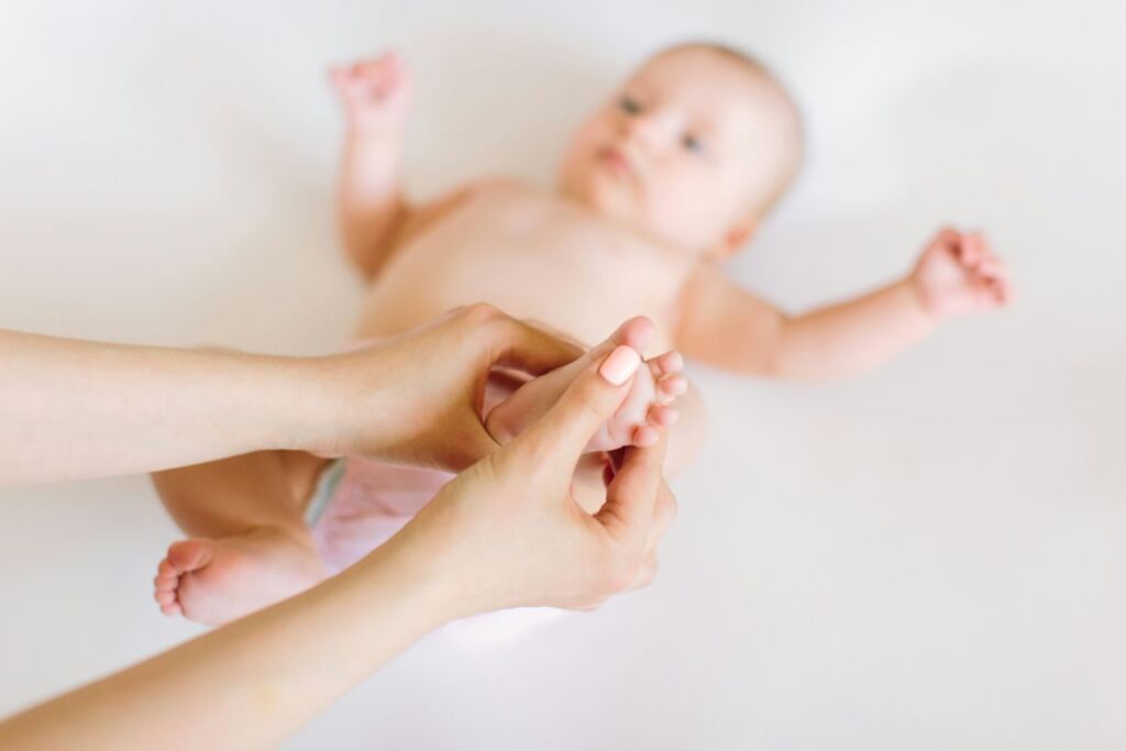Baby wird von der Mutter an den Füssen massiert