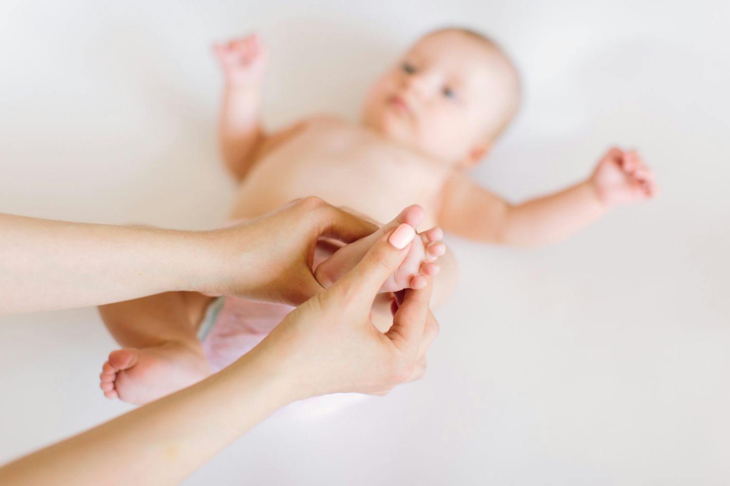 Baby wird von der Mutter an den Füssen massiert